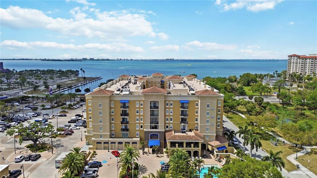 An aerial view shows a multi-story yellow hotel building with a pool and parking lot — 1064 N TAMIAMI TRAIL UNIT 1406, SARASOTA, FL