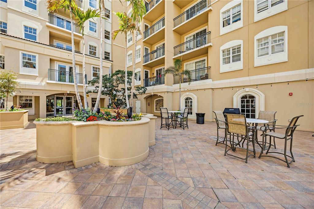 An outdoor patio area features paved flooring, patio furniture, and a central raised garden bed — 1064 N TAMIAMI TRAIL UNIT 1406, SARASOTA, FL