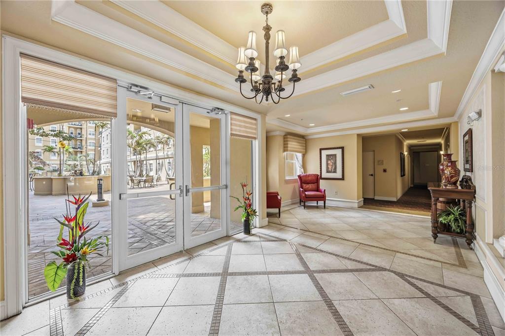 A bright lobby with tile floors, a chandelier, and glass doors leading to a patio — 1064 N TAMIAMI TRAIL UNIT 1406, SARASOTA, FL