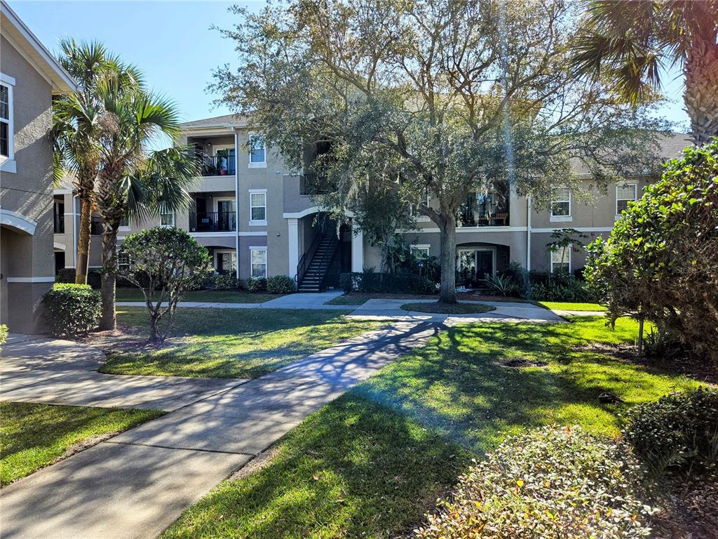 A multi-story apartment building with balconies, a central staircase, and surrounding landscaping — 6548 SWISSCO DRIVE UNIT 628, ORLANDO, FL