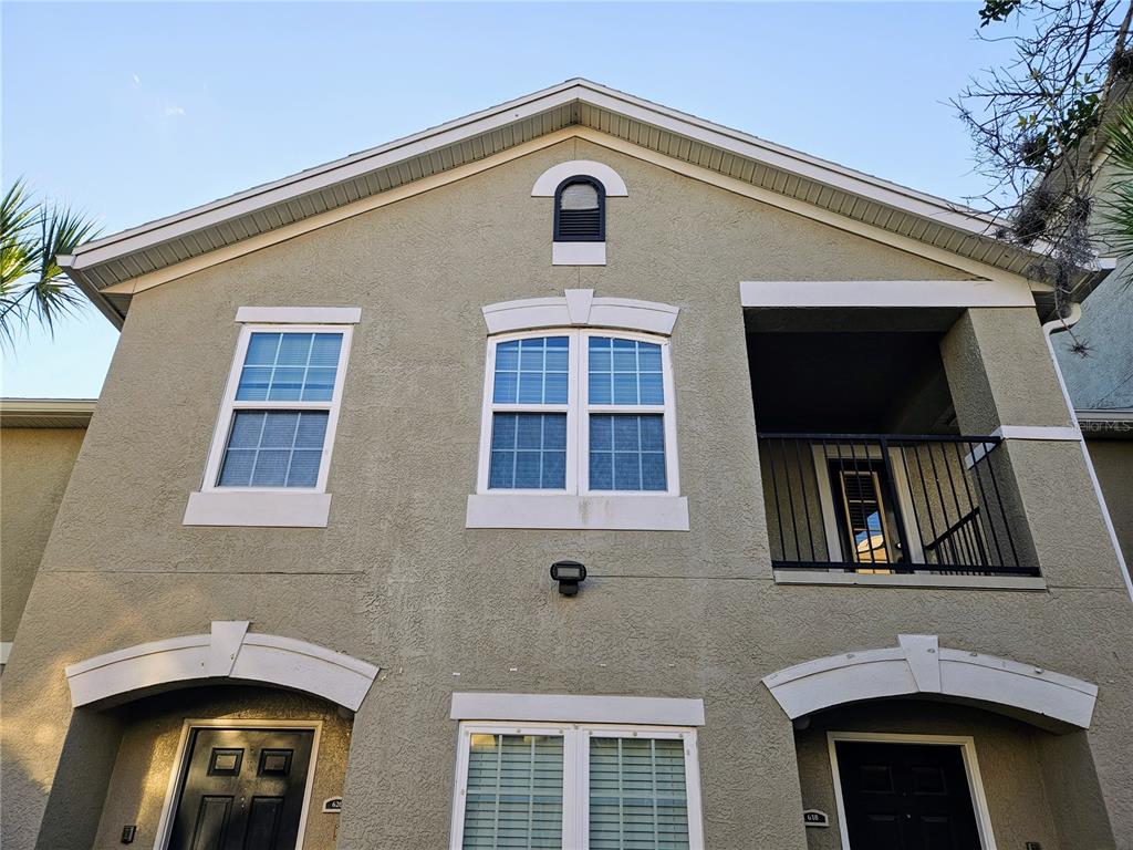 The exterior of a two-story stucco building features two front doors, windows, and a balcony — 6548 SWISSCO DRIVE UNIT 628, ORLANDO, FL