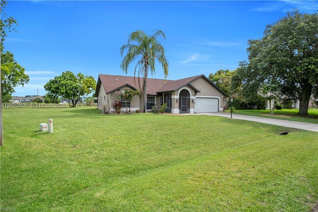 A single-story house with a brown roof, beige stucco exterior, and a two-car garage — 538 Whispering Wind Bnd, Lehigh Acres FL 33974, LEHIGH ACRES, FL