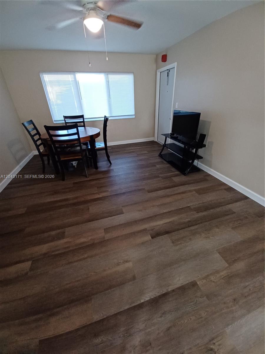 A dining area features wood-look flooring, a ceiling fan, a round table, and a television stand — HOLLYWOOD, FL