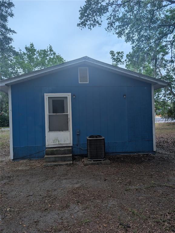 The exterior of a blue house features a white screen door, concrete steps, and an AC unit — 25007 NW 6TH AVENUE, NEWBERRY, FL