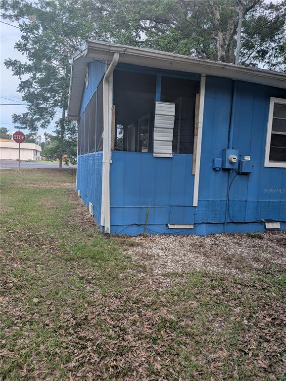 The exterior of a blue house features a screened-in porch with a metal panel patch — 25007 NW 6TH AVENUE, NEWBERRY, FL