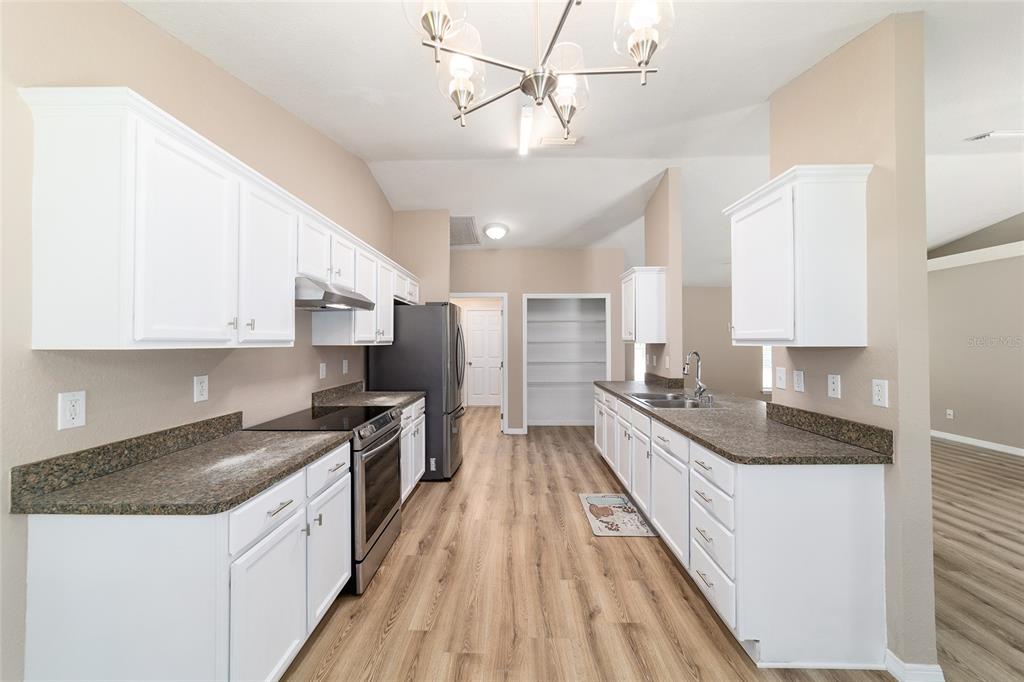 A kitchen with white cabinets, dark countertops, stainless steel appliances, and wood-look flooring — 5315 SE 26TH AVENUE, OCALA, FL