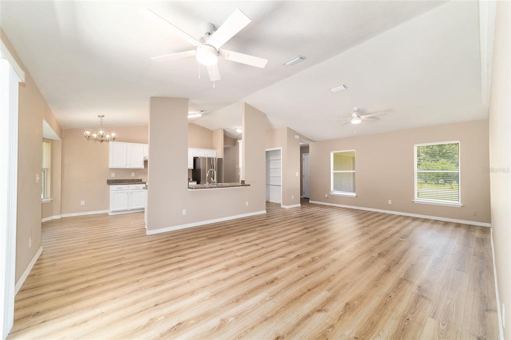 An open-concept living and dining area with light wood-look flooring and white ceiling fans — 5315 SE 26TH AVENUE, OCALA, FL