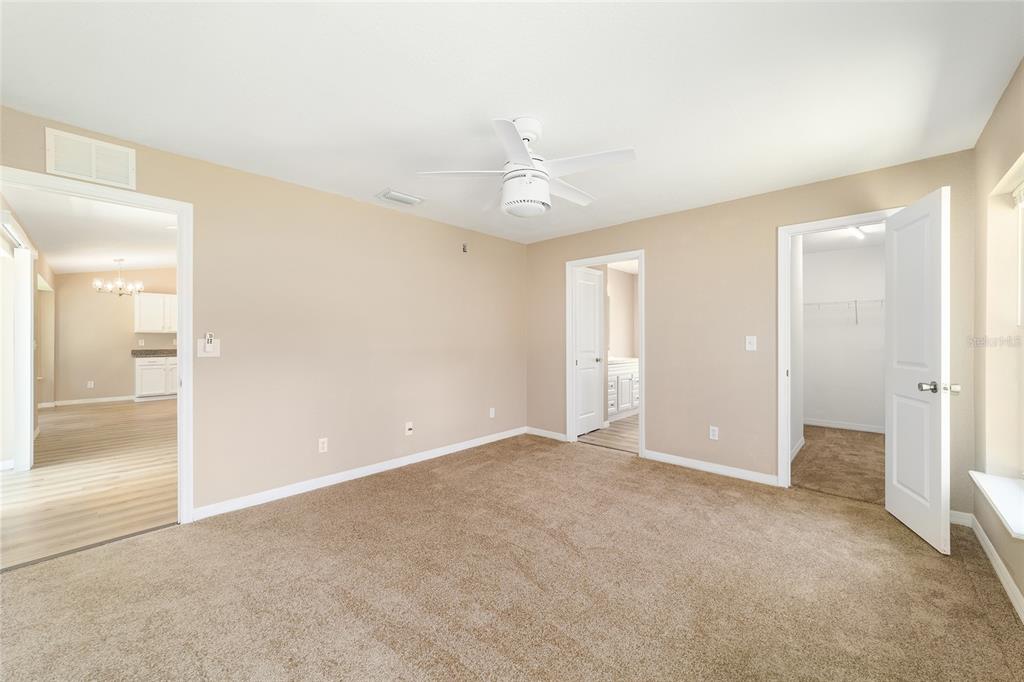A carpeted bedroom with a ceiling fan, two doorways, and a view into another room — 5315 SE 26TH AVENUE, OCALA, FL