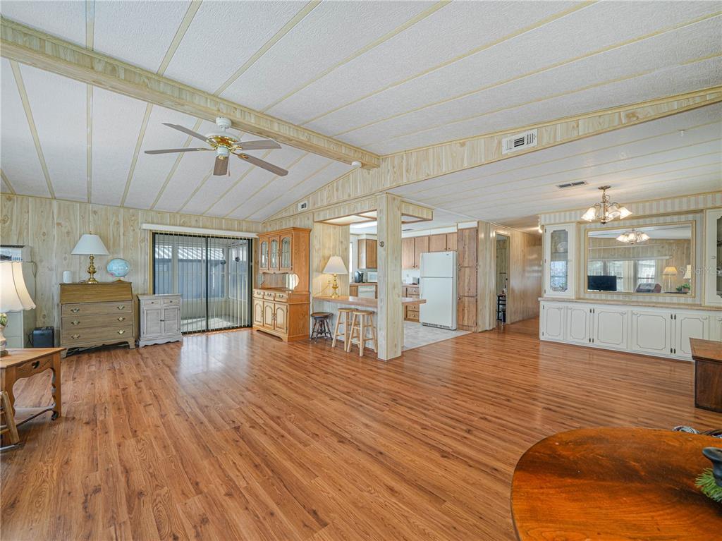 A spacious living room features wood-look flooring, wood paneling, and an open kitchen area — 1679 FOXWAY DRIVE, LAKELAND, FL