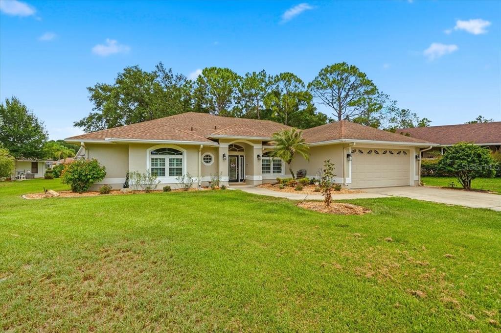 A single-story suburban house with a tan stucco exterior, brown roof, and attached garage — 3158 BEAUCHAMP COURT, WINTER HAVEN, FL