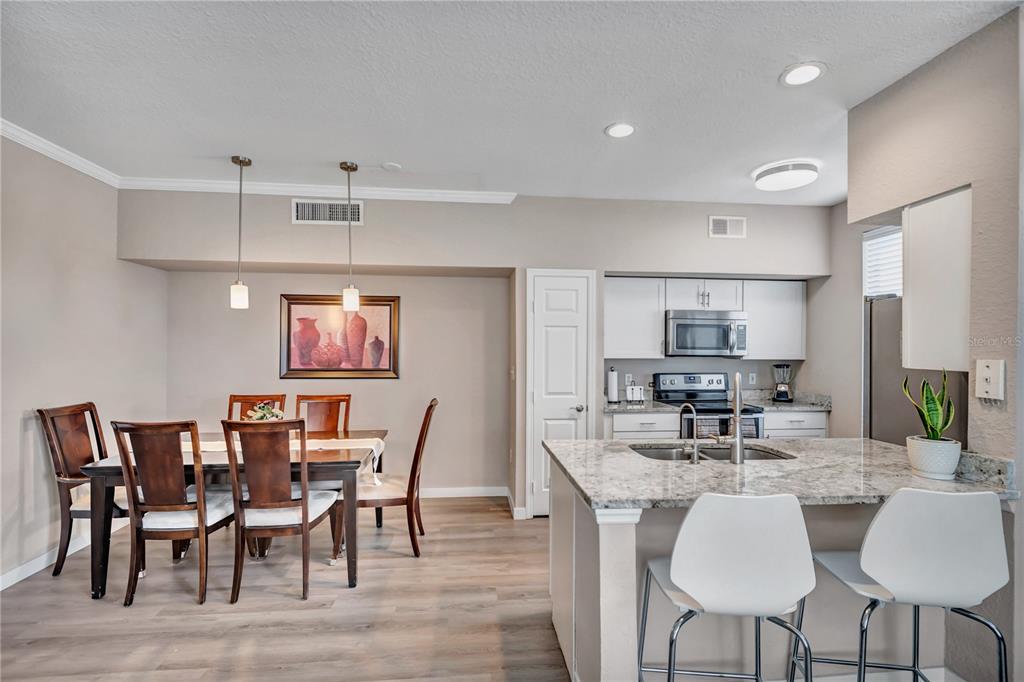 A dining area with a wooden table and chairs sits adjacent to a modern kitchen — 9834 LAKE CHASE ISLAND WAY UNIT 9834, TAMPA, FL