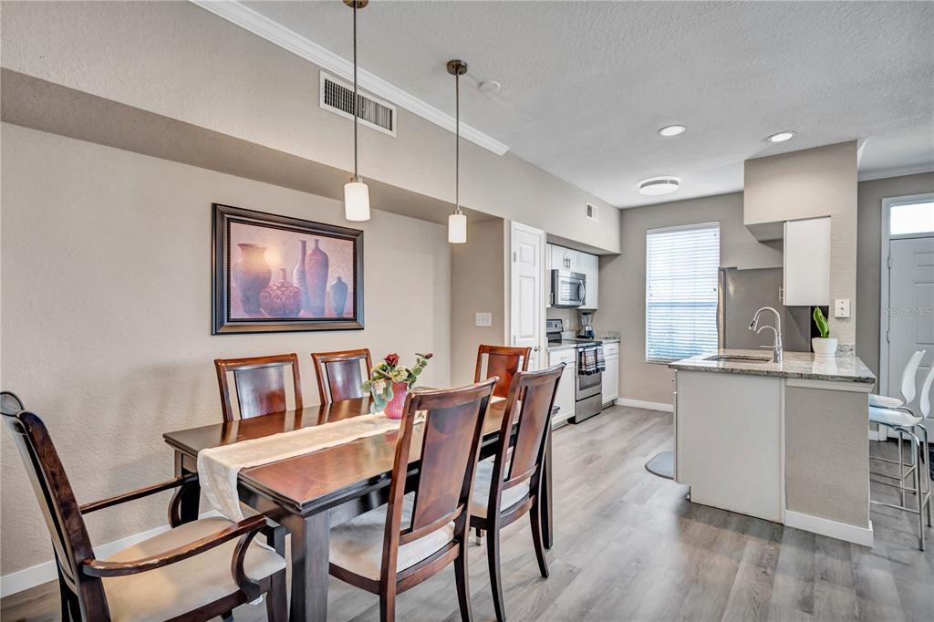 A dining area with a wooden table and chairs sits adjacent to a modern kitchen — 9834 LAKE CHASE ISLAND WAY UNIT 9834, TAMPA, FL