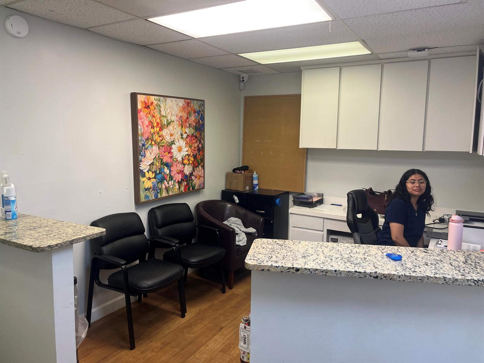 A reception area features a granite-topped desk, black chairs, a floral painting, and white cabinetry — 1708 N Federal Highway, FL 33460, FL