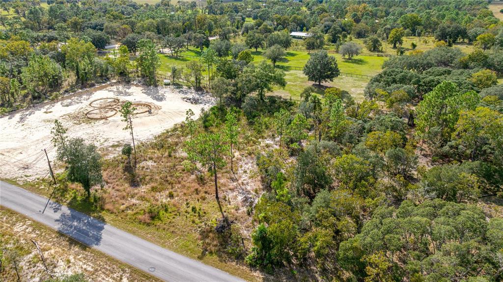 An aerial view shows a sandy lot with a circular track next to a road — LOT 10 SE 125TH COURT, DUNNELLON, FL