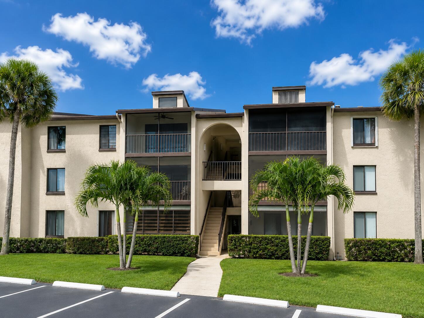 A three-story apartment building with screened balconies, palm trees, and a central stairwell — 627 Sea Pine Way # C2, FL 33415, FL