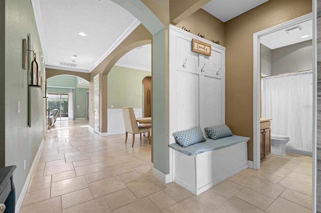 A hallway features tile flooring, a white mudroom bench, and an arched entryway to a dining area — 5210 SPARROWGLEN PLACE, LITHIA, FL