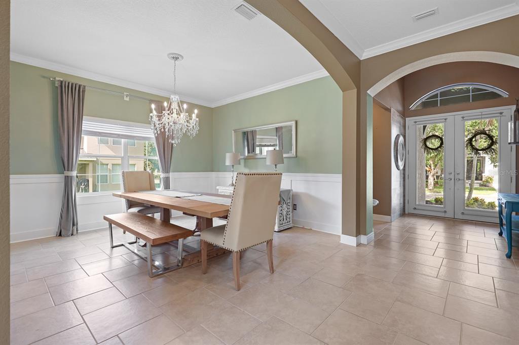 A dining room with a chandelier, wooden table, bench, upholstered chairs, and an entryway — 5210 SPARROWGLEN PLACE, LITHIA, FL
