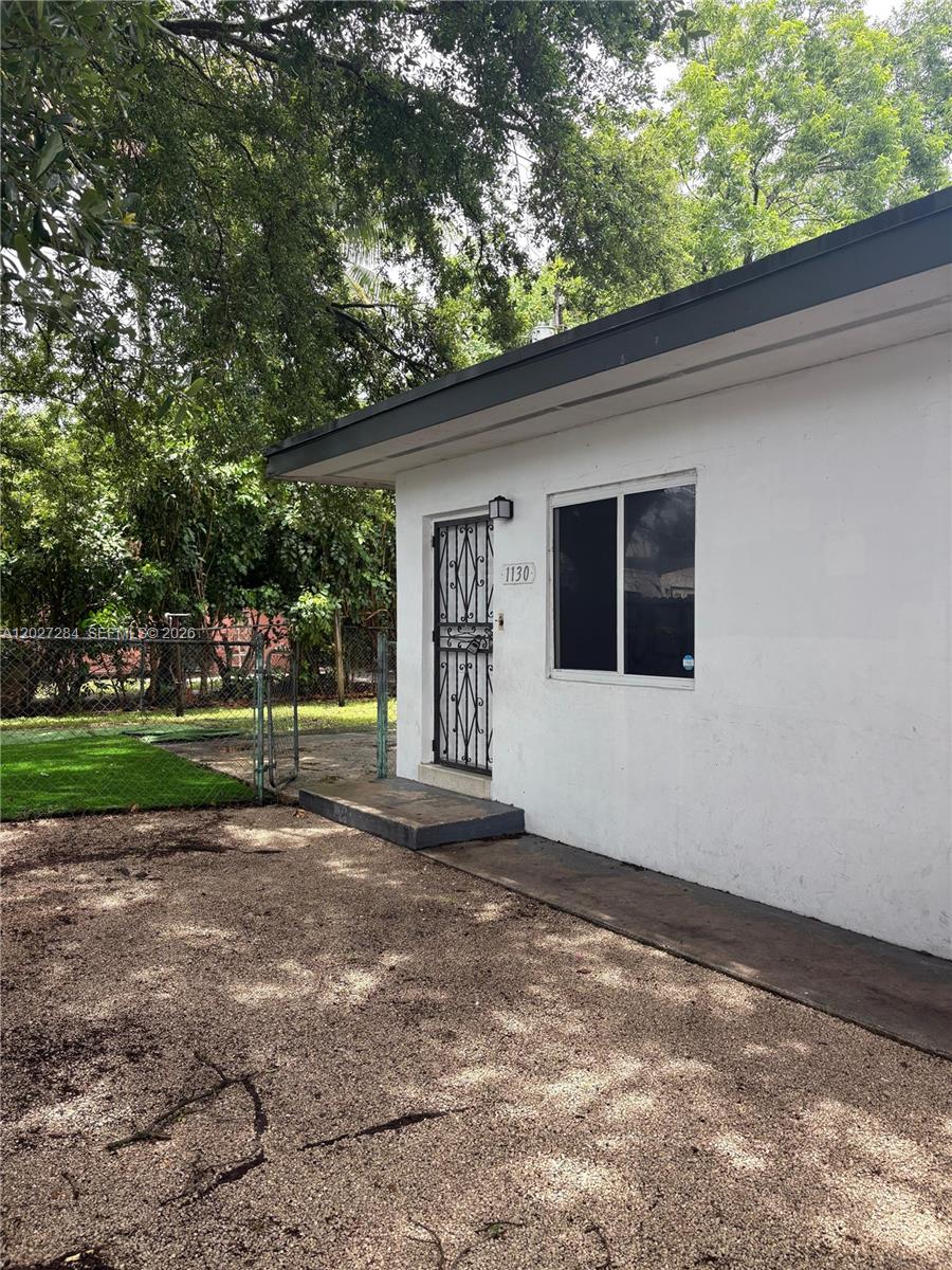 A white exterior wall features a single window and a door with a security gate — 1130 NW 76th St # 1130, Miami FL 33150, MIAMI, FL