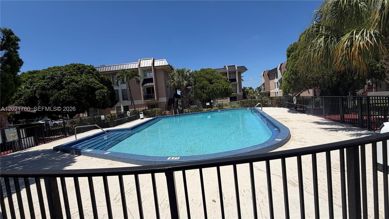 A rectangular swimming pool is surrounded by a black metal fence and apartment buildings — 3901 SW 109th Ave # 4, Miami FL 33165, MIAMI, FL