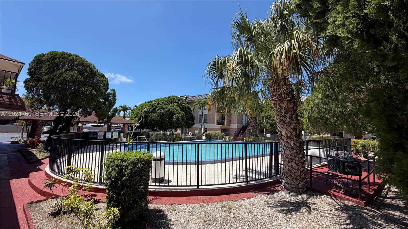 A fenced swimming pool area is surrounded by palm trees and multi-story residential buildings — 3901 SW 109th Ave # 4, Miami FL 33165, MIAMI, FL