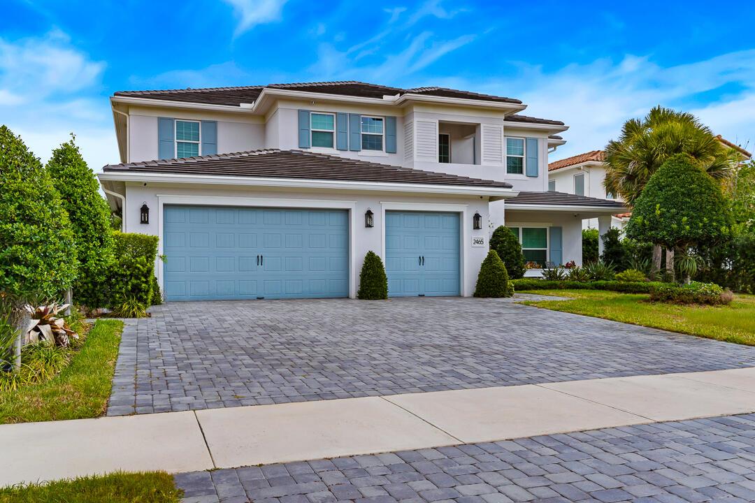 A two-story suburban house features a three-car garage, light-colored siding, and a paved driveway — 2465 NE Evinrude Circle, Jensen Beach FL 34957, JENSEN BEACH, FL