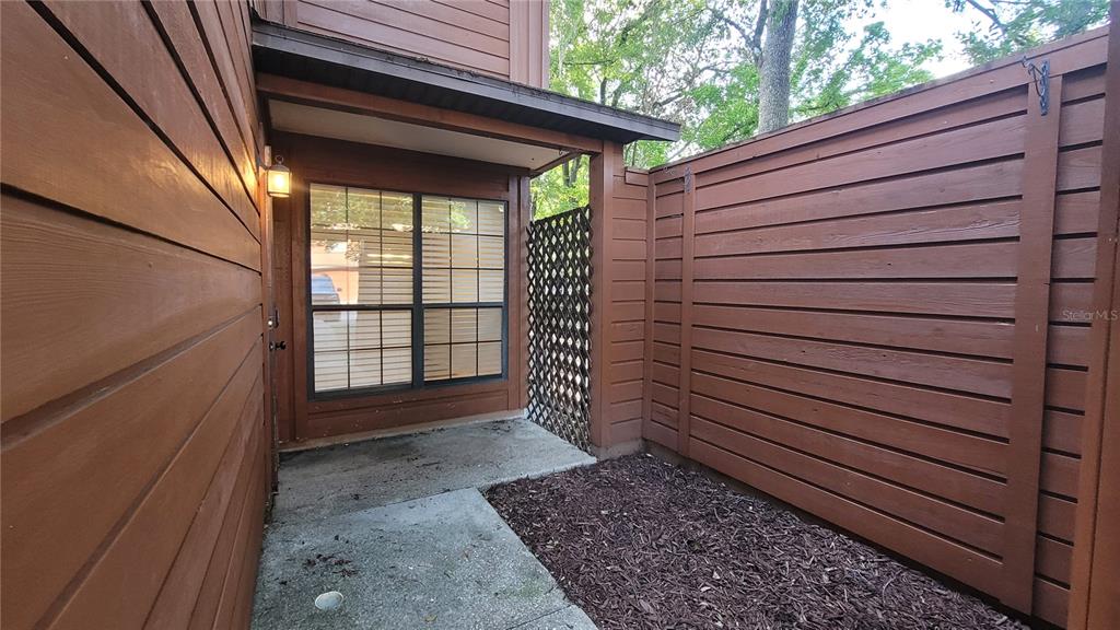 A wooden privacy fence encloses a small concrete patio area next to a building exterior — 819 SW 57TH TERRACE, GAINESVILLE, FL
