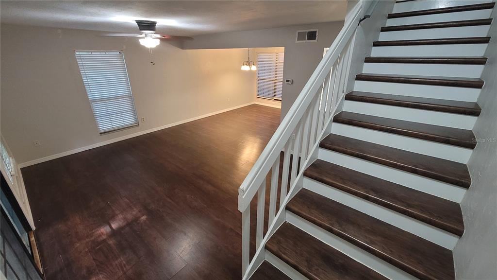 An interior view shows a living area with dark wood floors and a wooden staircase — 819 SW 57TH TERRACE, GAINESVILLE, FL
