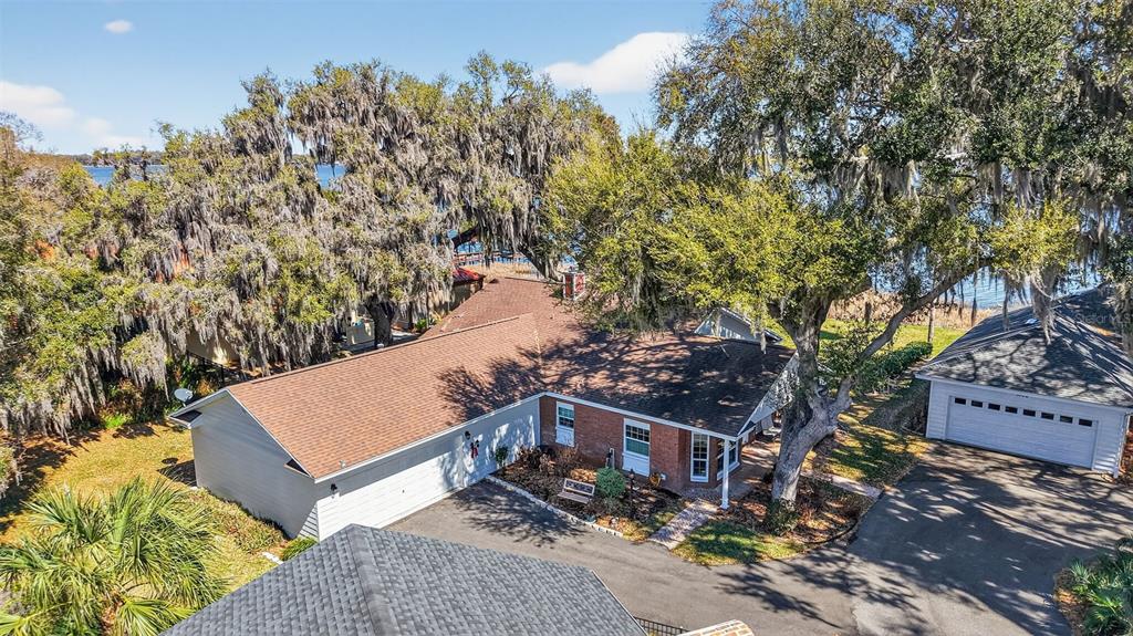An aerial view shows a single-story brick and siding house with a detached garage — 1404 REGENCY COURT, LEESBURG, FL