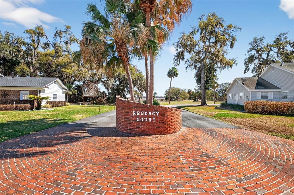 A brick entrance sign for Regency Court sits in front of a circular brick driveway — 1404 REGENCY COURT, LEESBURG, FL