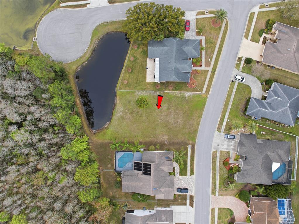 An aerial view shows a vacant residential lot situated between two houses and a pond — 1522 HAVERHILL DRIVE, NEW PORT RICHEY, FL