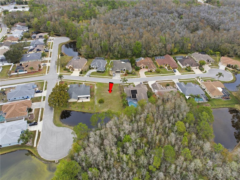 An aerial view shows a vacant residential lot situated between two houses near a pond — 1522 HAVERHILL DRIVE, NEW PORT RICHEY, FL