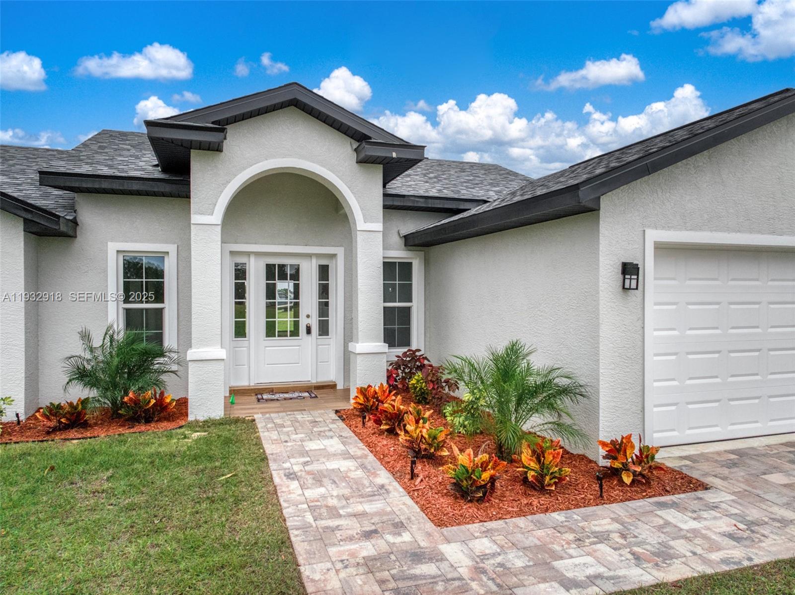 The exterior of a single-story house features a paved walkway, landscaped beds, and a garage — 6724 Heavitree DR, Sebring FL 33876, SEBRING, FL