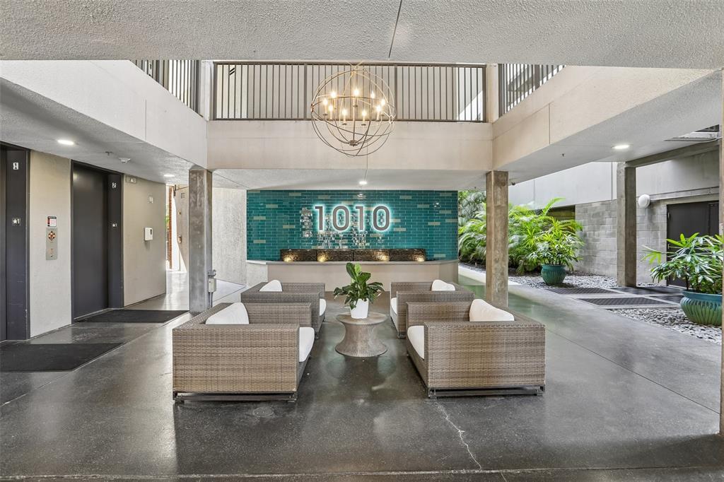 An open-air lobby features a seating area with wicker furniture and a teal tiled wall — 1010 CENTRAL AVENUE UNIT 413, ST PETERSBURG, FL