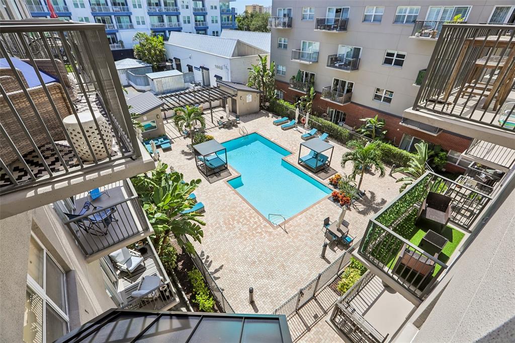 An elevated view of a courtyard featuring a swimming pool, lounge chairs, and apartment balconies — 1010 CENTRAL AVENUE UNIT 413, ST PETERSBURG, FL