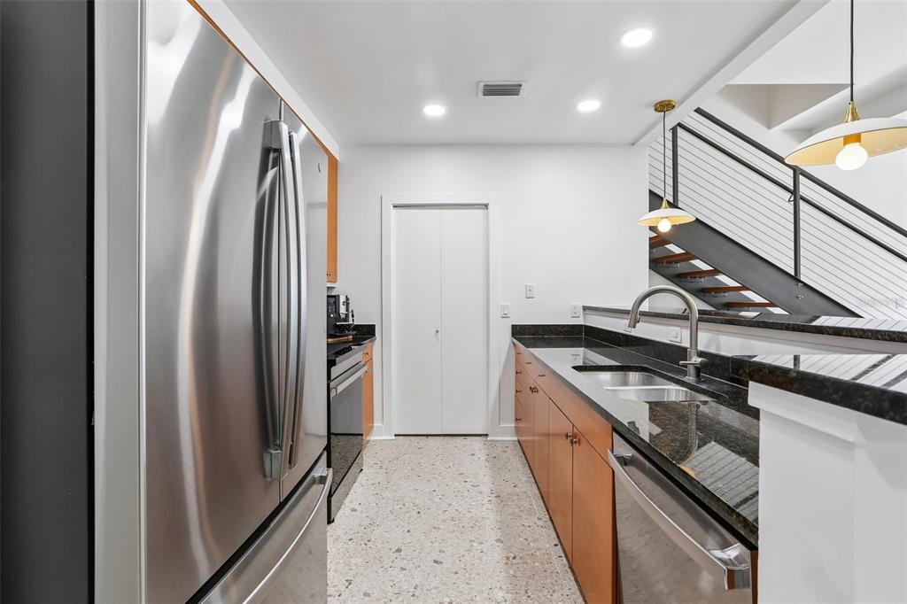 A kitchen features stainless steel appliances, wood cabinets, dark granite countertops, and terrazzo flooring — 1010 CENTRAL AVENUE UNIT 413, ST PETERSBURG, FL
