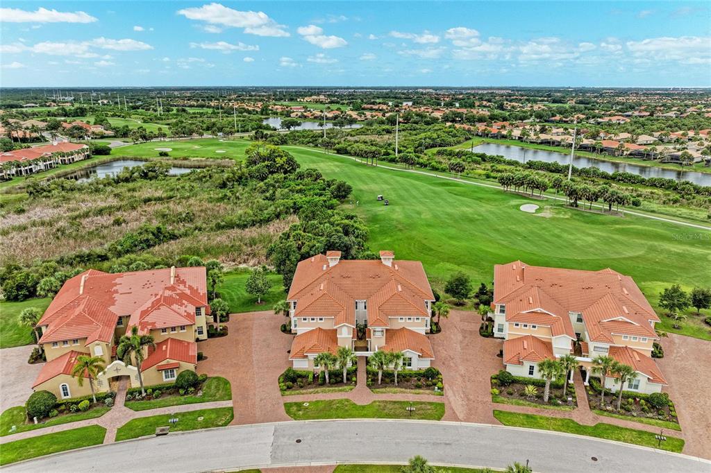An aerial view shows three multi-story residential buildings with orange tile roofs overlooking a golf course — 202 BELLA VISTA TERRACE UNIT 28D, NOKOMIS, FL