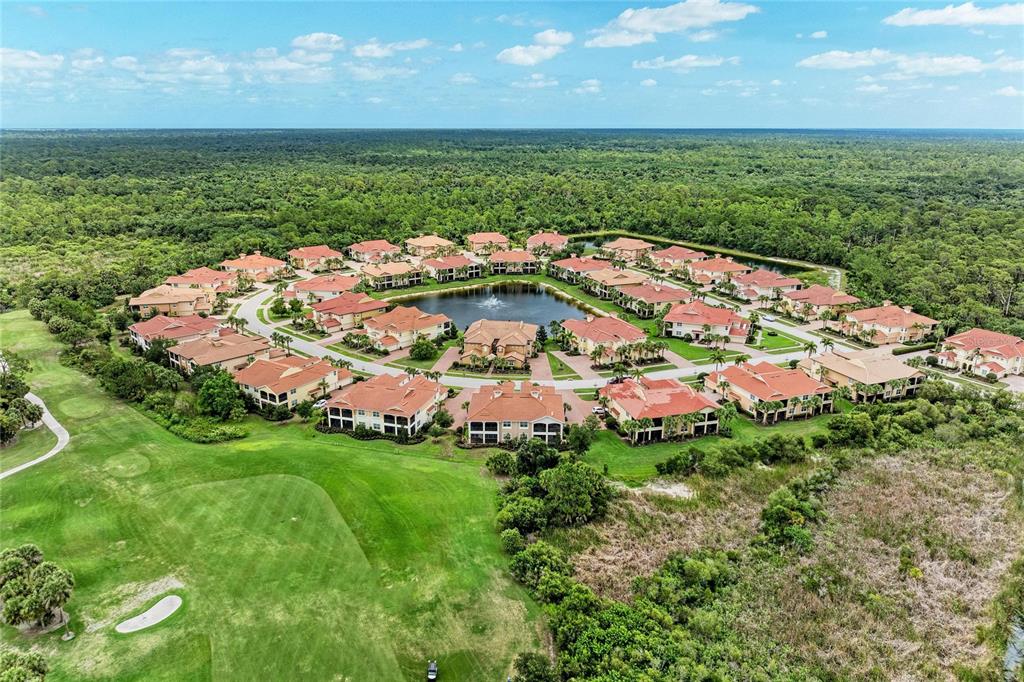 An aerial view of a residential complex with multi-story buildings surrounding a central pond — 202 BELLA VISTA TERRACE UNIT 28D, NOKOMIS, FL