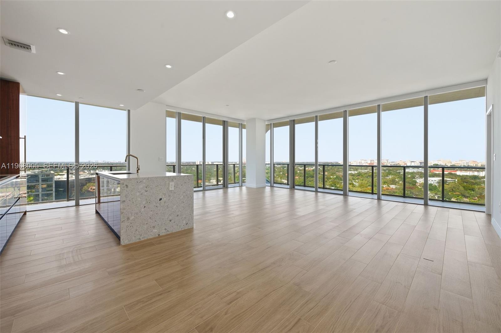 A modern, open-concept living area features light wood flooring, a kitchen island, and floor-to-ceiling windows — 2678 Tigertail Ave # 1501, Miami FL 33133, MIAMI, FL