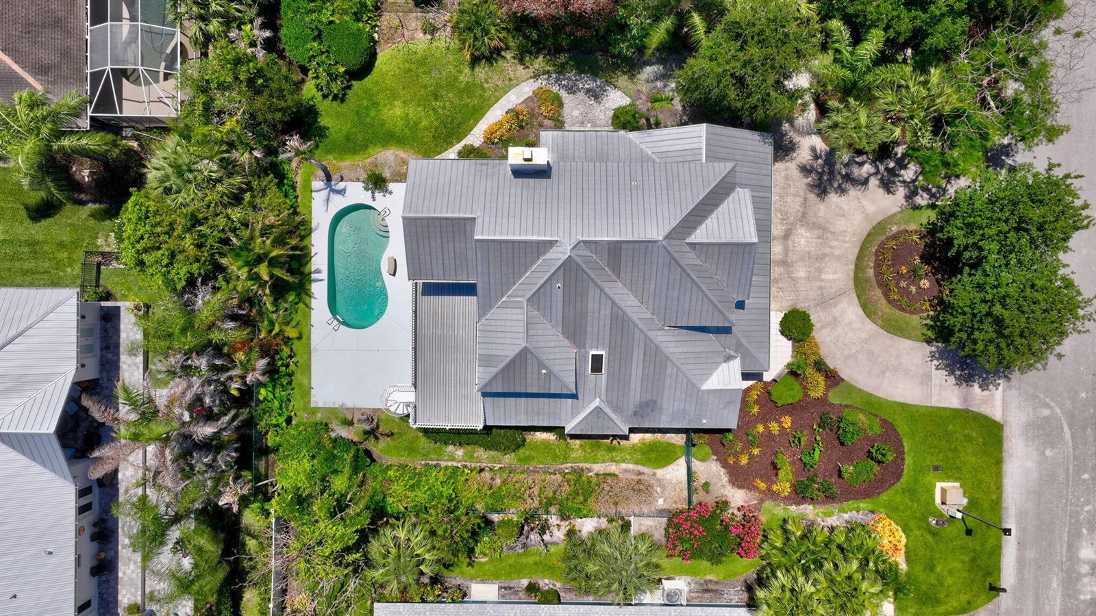An aerial view shows a house with a metal roof, a pool, and landscaped grounds — 23 Sea Gull Place, Vero Beach FL 32960, VERO BEACH, FL