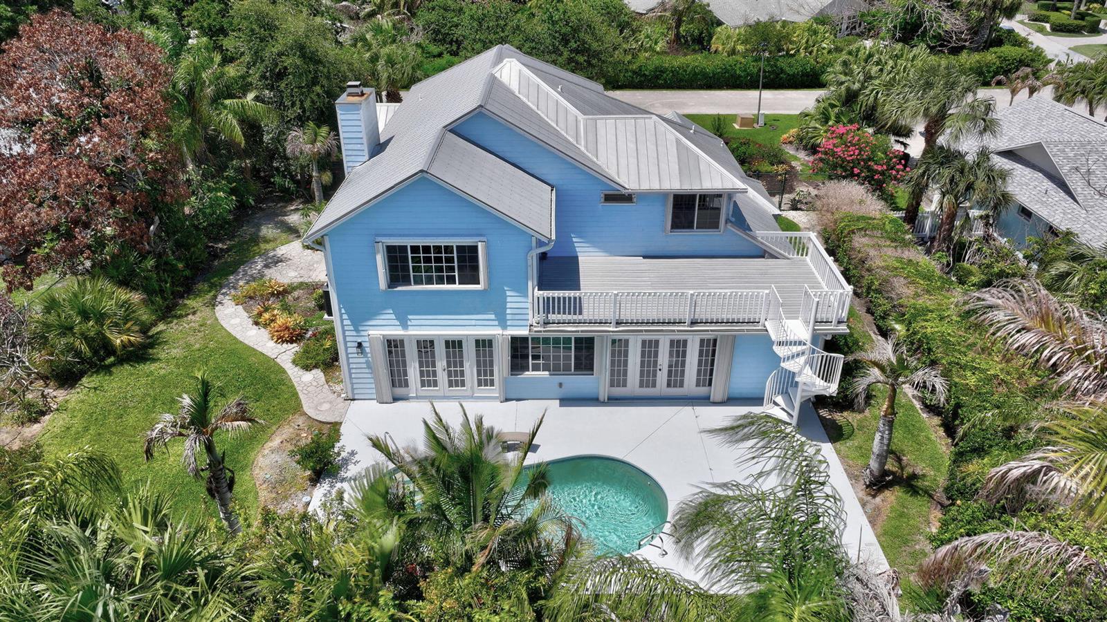 An aerial view of a blue two-story house with a metal roof and backyard pool — 23 Sea Gull Place, Vero Beach FL 32960, VERO BEACH, FL