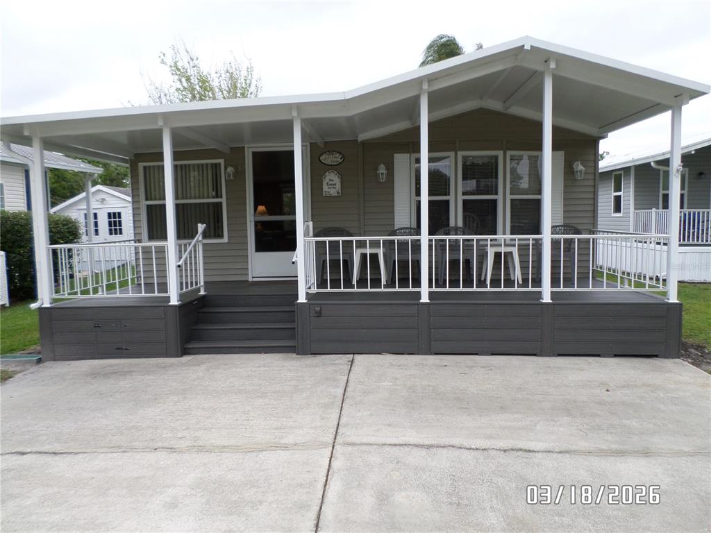 A manufactured home features a covered front porch with white railings and gray skirting — 37 APPALOOSA TRAIL, LAKE WALES, FL