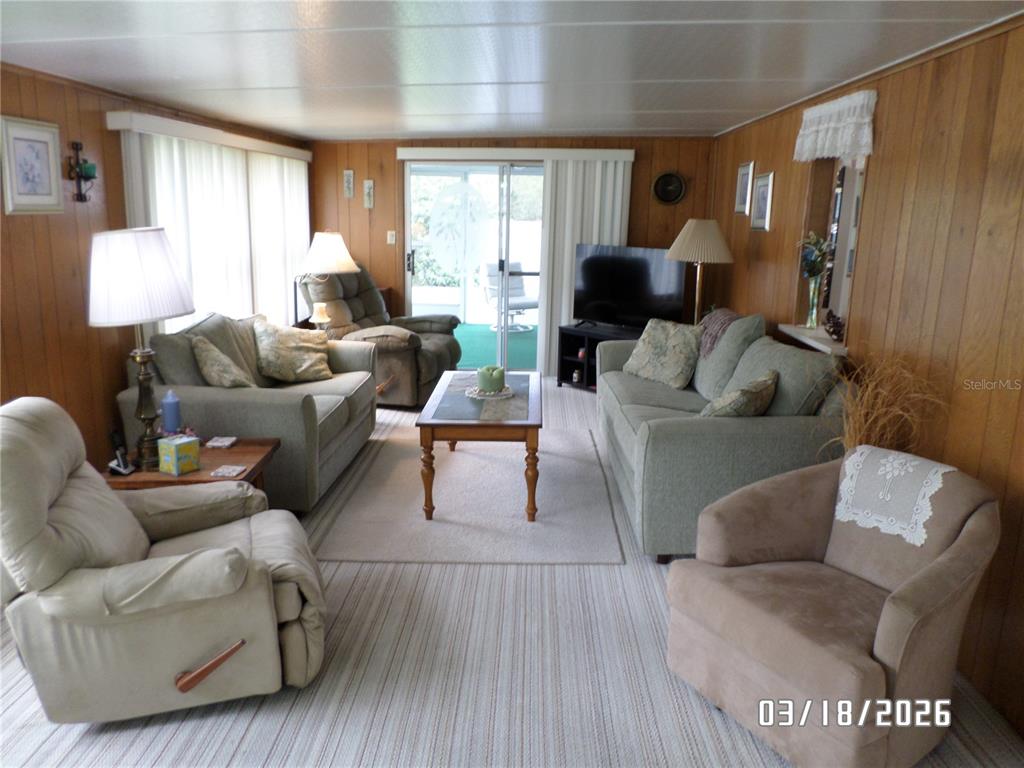 A living room features wood-paneled walls, carpeted flooring, two sofas, and several armchairs — 37 APPALOOSA TRAIL, LAKE WALES, FL