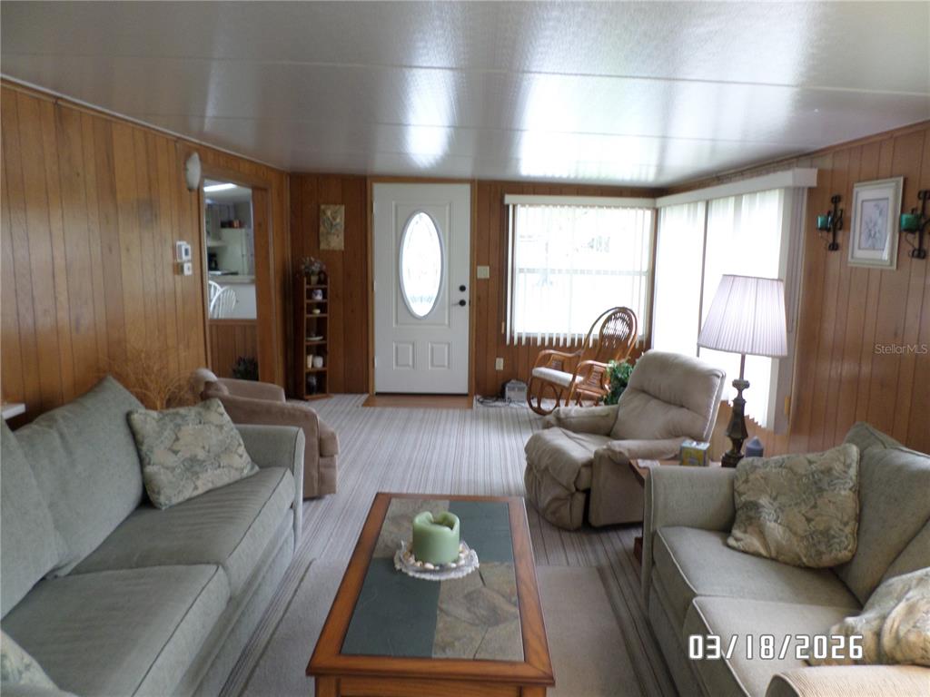 A living room features wood-paneled walls, a white front door, and two light-colored sofas — 37 APPALOOSA TRAIL, LAKE WALES, FL