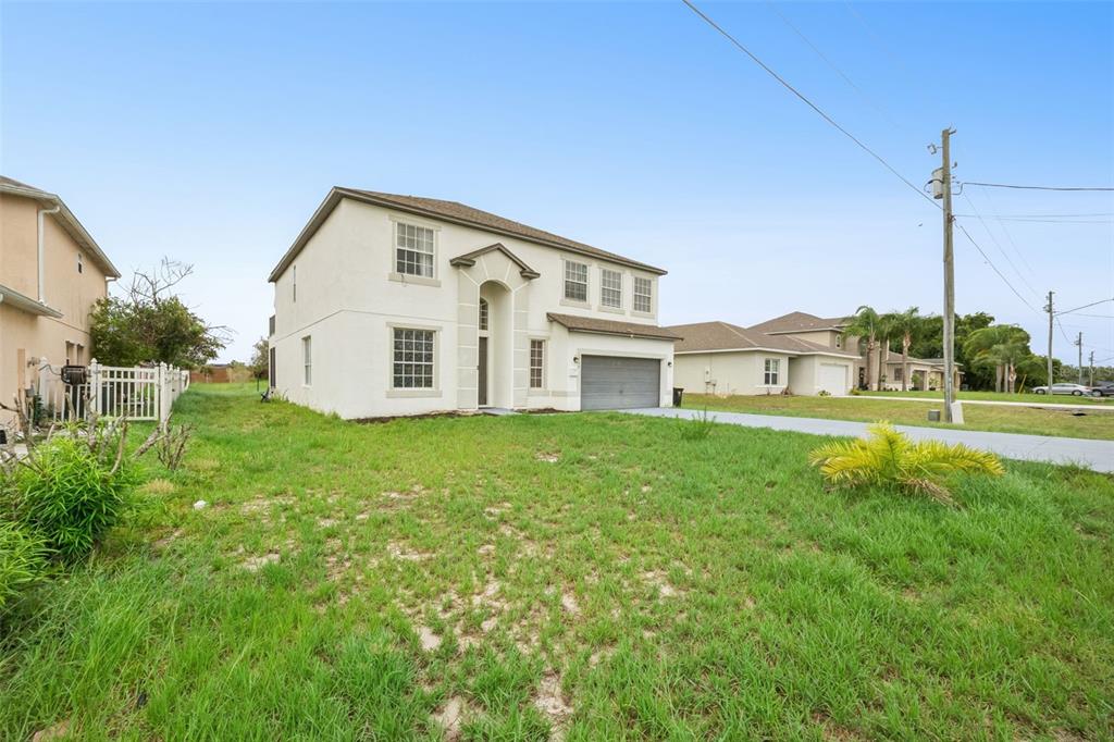 A two-story, light-colored stucco house with a garage and a large, grassy front yard — 1853 SUPERIOR COURT, POINCIANA, FL