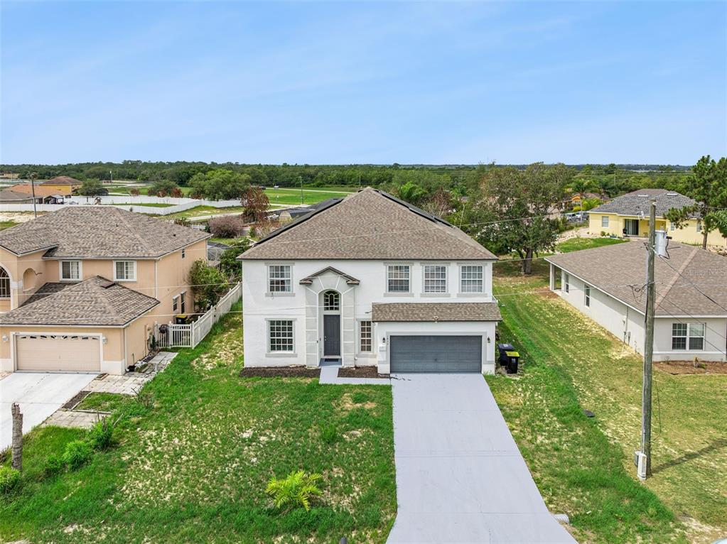 An aerial view of a two-story suburban house with a gray roof and concrete driveway — 1853 SUPERIOR COURT, POINCIANA, FL