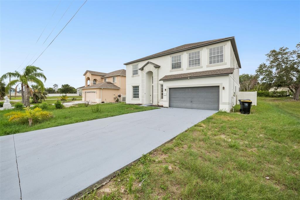 A two-story white stucco house with a gray garage door and a concrete driveway — 1853 SUPERIOR COURT, POINCIANA, FL