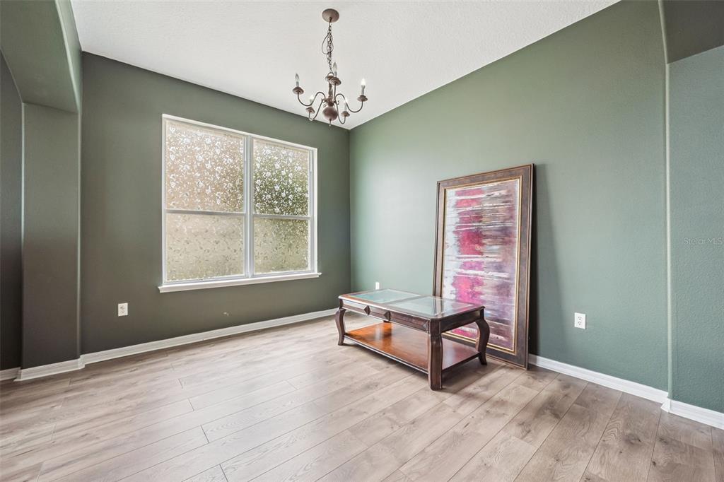 A room with green walls, wood-look flooring, a chandelier, a window, and a coffee table — 1853 SUPERIOR COURT, POINCIANA, FL