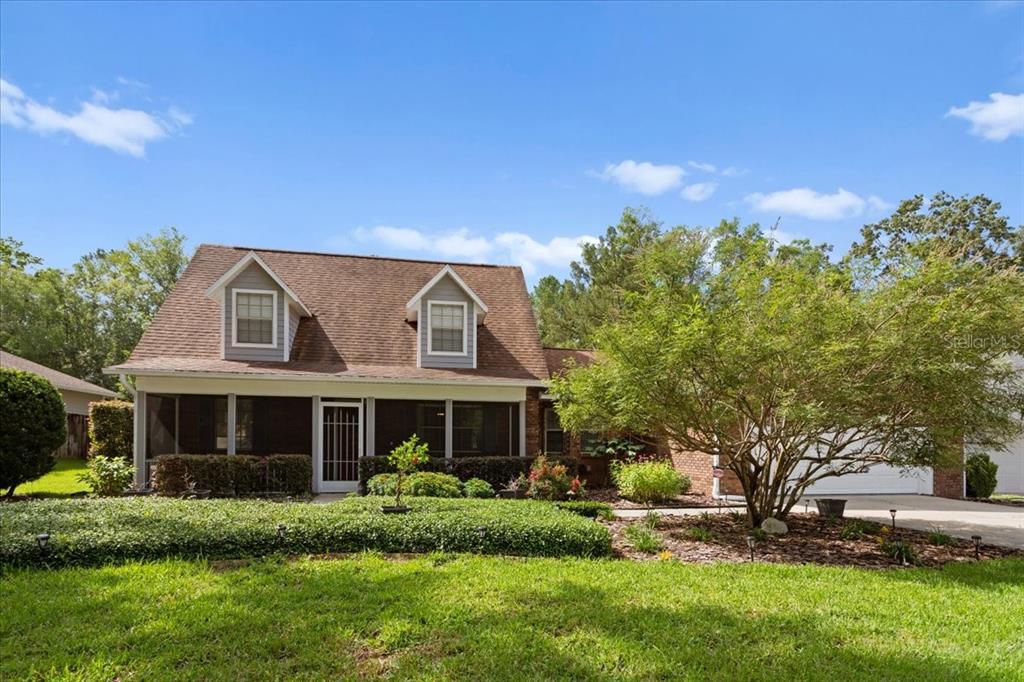 A two-story house with a screened front porch, two dormer windows, and a landscaped yard — 11617 NW 13TH LANE, GAINESVILLE, FL