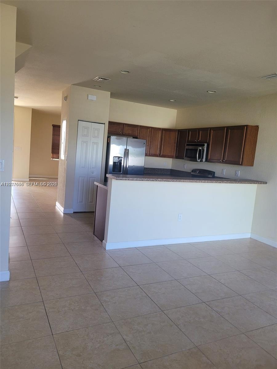 This kitchen features dark wood cabinets, stainless steel appliances, and a breakfast bar — 3537 W 89th Pl, Hialeah FL 33018, HIALEAH, FL