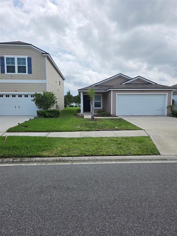 Two suburban houses stand side-by-side with concrete driveways and green lawns under a cloudy sky — 754 GRAND RESERVE DRIVE, BUNNELL, FL